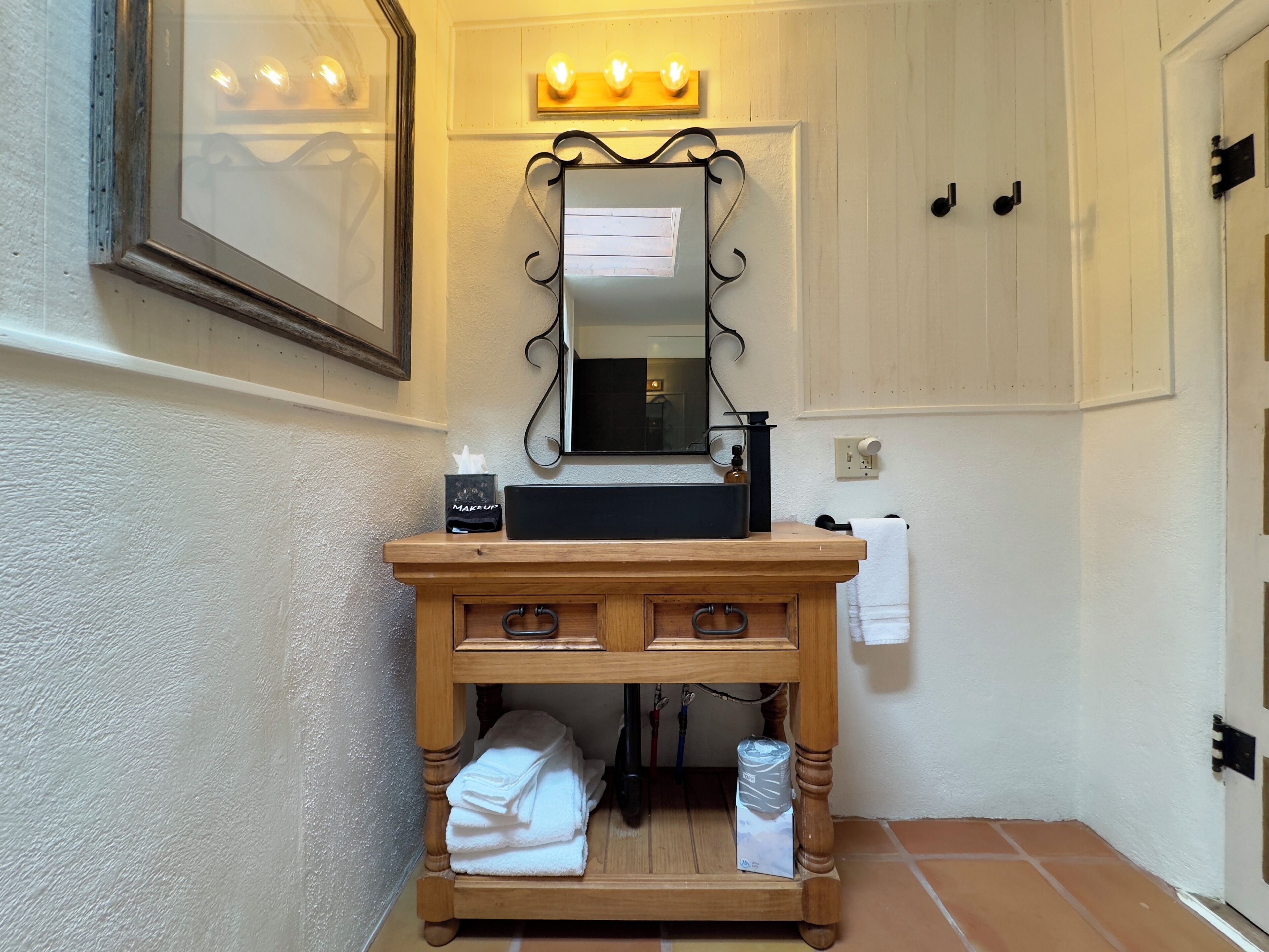 A bathroom with a wooden vanity, a mirror, a sink, and a towel rack.