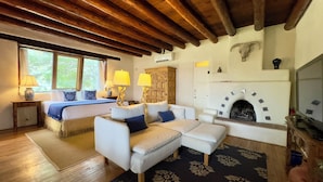 Une pièce avec un plafond en bois, une cheminée, un lit, un canapé et un téléviseur.