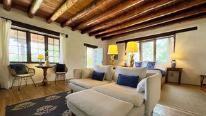 Une pièce chaleureuse avec un plafond en bois, un canapé, un fauteuil, une petite table et un lit avec une table de chevet.