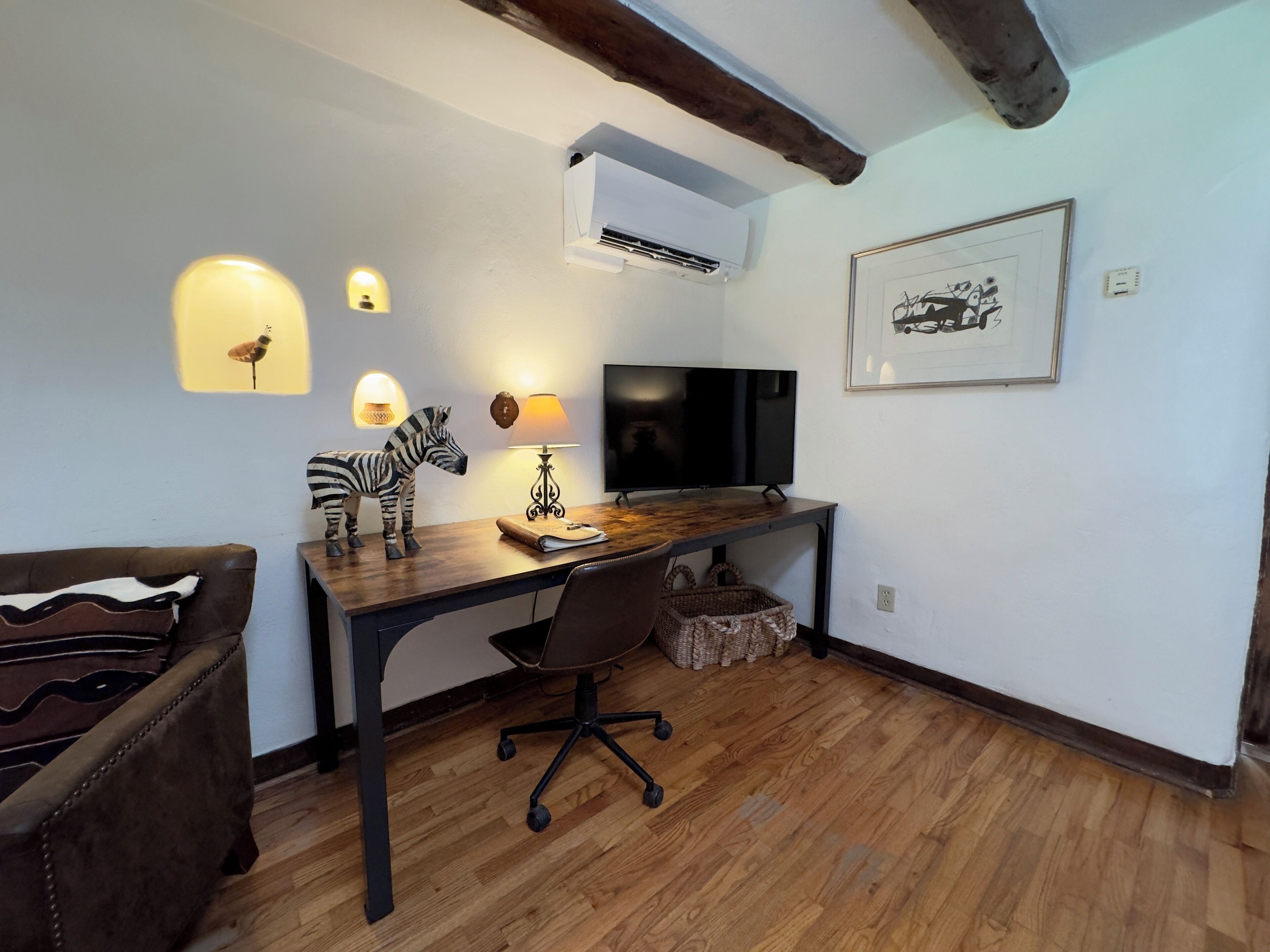 Une pièce chaleureuse avec un bureau en bois, un fauteuil confortable, une figurine de zèbre, une lampe et un tableau encadré au mur.