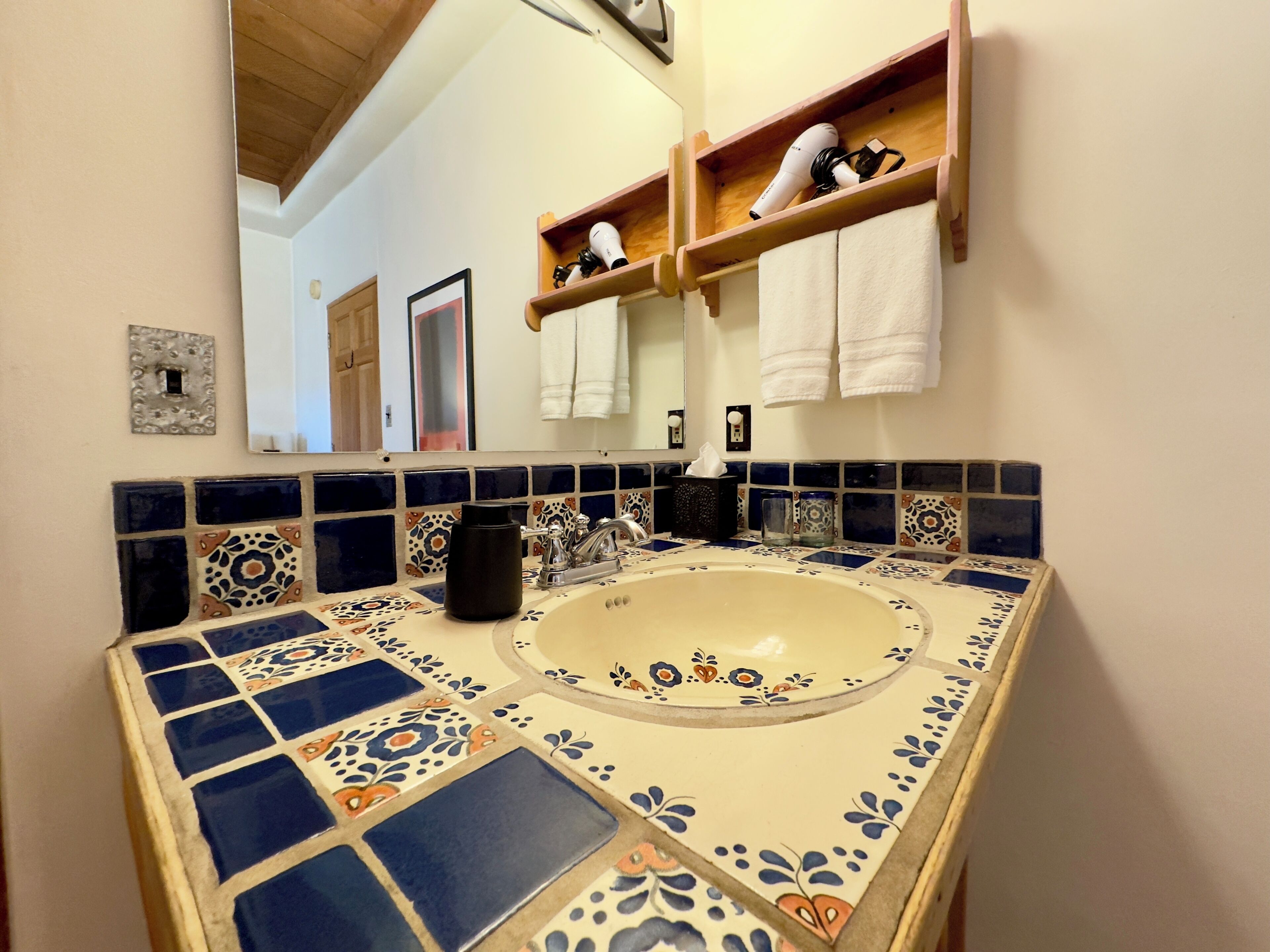 A bathroom with a sink, mirror, and shelves with towels.
