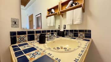 A bathroom with a sink, mirror, and shelves with towels.