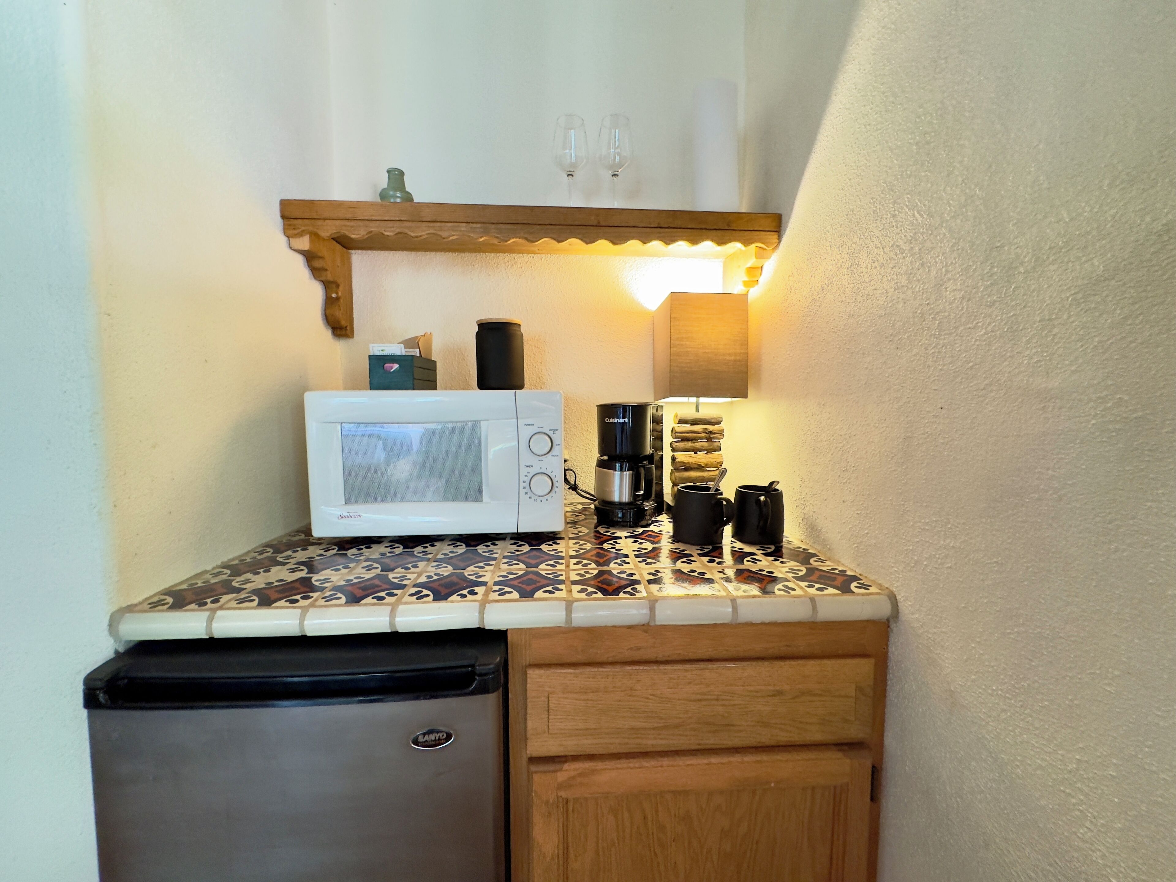A compact kitchenette with a microwave, coffee maker, and a small refrigerator.