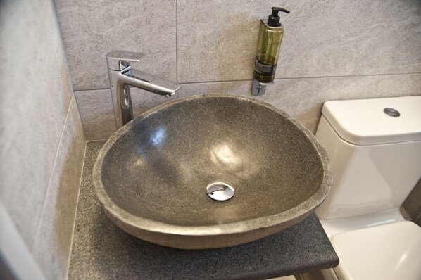 A bathroom with a stone sink, a modern faucet, and a toilet. - Chalkida Apartments (Chalcis)