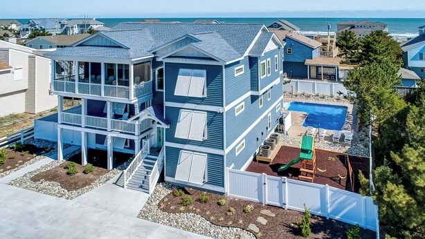 Een tweelaags huis met een balkon, een zwembad en uitzicht op de oceaan.