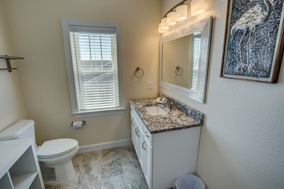 A bathroom with a toilet, sink, and window.