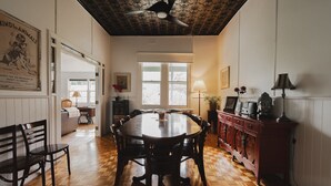 A dining room with a wooden table and chairs, a ceiling fan, and a view of the outdoors through large windows. - White Rose Cottage Healesville (Healesville)