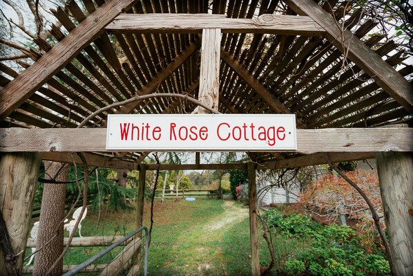 Eine Hollaube mit einem Schild, auf dem 'White Rose Cottage' steht.