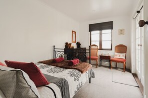 Ein Schlafzimmer mit einem Bett, einem Sessel, einem Schminktisch und einem Fenster.