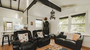 A living room with a black leather sofa set, a wooden coffee table, and a patterned rug. - White Rose Cottage Healesville (Healesville)