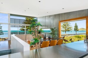 A modern kitchen with a large island, seating area, and a view of the sea.