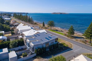 A coastal residential area with modern houses, a road, and a view of the sea.