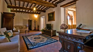 Una sala acogedora con un sofá, un televisor, un aparador de madera y una alfombra estampada.
