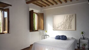 Un dormitorio con una cama grande, una ventana, un cuadro y una mesita de noche con una lámpara.