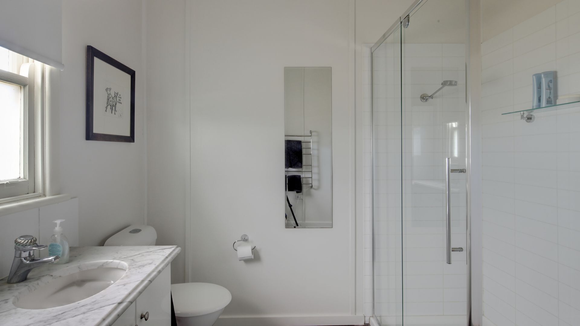 Un bagno con lavandino bianco, WC e doccia con pareti in vetro.