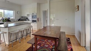 Une cuisine moderne dotée d’un îlot central, de tabourets de bar et d’une table à manger en bois.