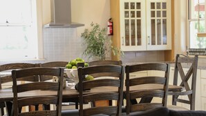 Un comedor con mesa y sillas de madera, un cuenco de fruta y una planta en maceta.