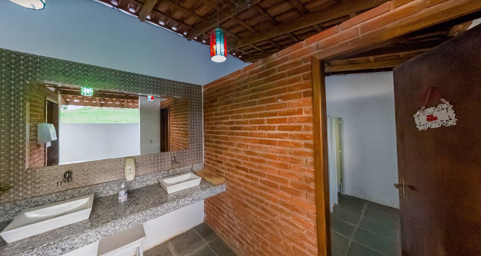 Een badkamer met een granieten aanrechtblad, een witte wastafel en een spiegel met een backsplash van groene tegels.