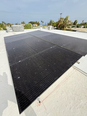 A rooftop with solar panels, a concrete structure, and a clear sky.