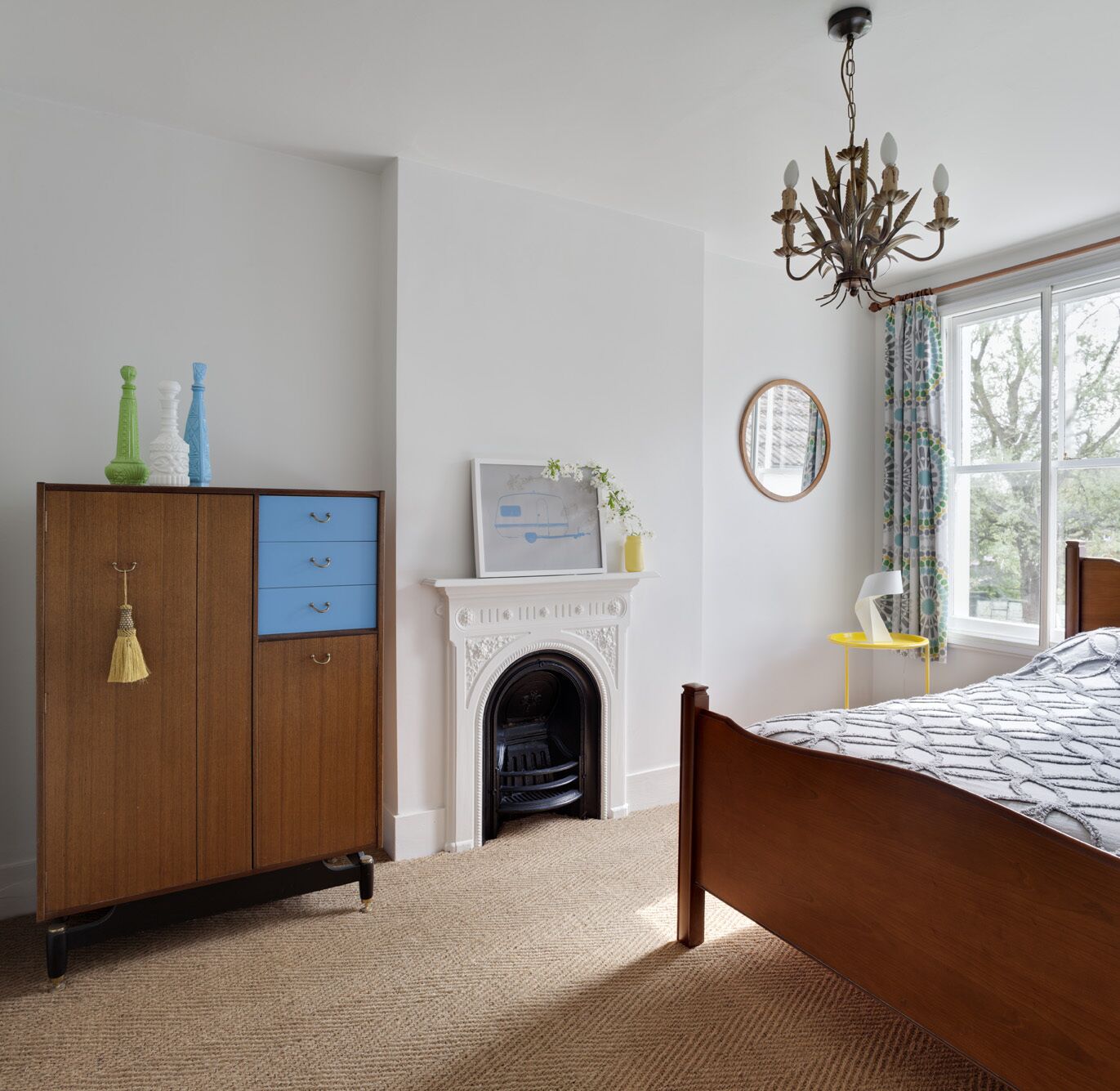 A bedroom with a wooden bed, a fireplace, a wardrobe, and a chandelier.