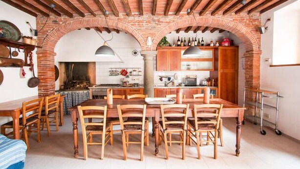 Una cocina rústica con arcos de ladrillo visto, mobiliario de madera y una variedad de electrodomésticos.