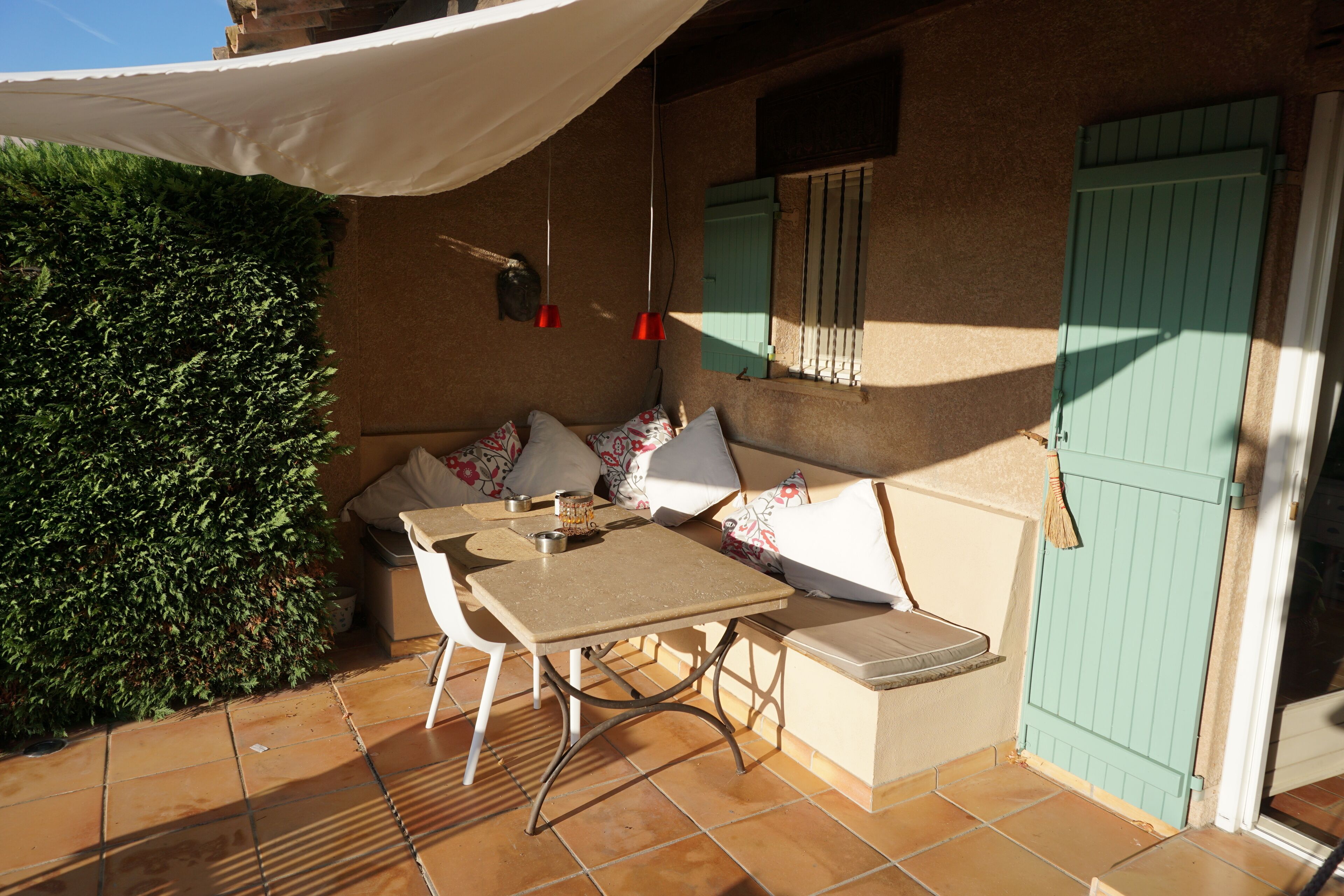 Un patio con una mesa, sillas, un banco acolchado y una puerta verde.