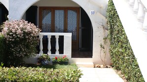 Un bâtiment à la façade blanche, doté d’une porte en bois et d’un balcon orné de balustrades blanches.