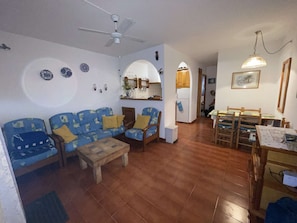 Uma sala de estar com sofá, cadeiras, mesa de centro e um espaço de jantar com mesa e cadeiras.