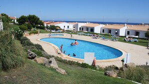 Une piscine entourée de chaises longues, avec vue sur la mer.