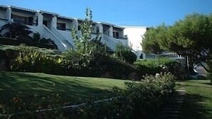 Un bâtiment à la façade blanche, doté de nombreuses fenêtres et d’un escalier menant à une zone abritée.