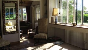 A cozy room with a large window, a chair, a table, and a mirror.