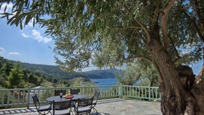 A stone patio with a table and chairs, overlooking a scenic view of a body of water and hills.