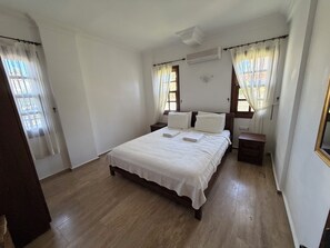 A bedroom with a wooden bed, white linens, a bedside table, a nightstand, and a window with curtains. - Villa with Private Pool, Gardens and Mountain Views (Mugla)