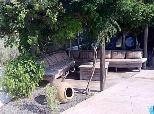 An outdoor seating area with a bench and a tree, a tire swing, and a wooden structure.