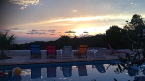 Zona junto a la piscina con sillones de descanso y vistas al atardecer.