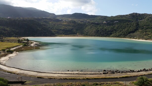 Un paisaje costero con una extensa masa de agua, una carretera y colinas circundantes.