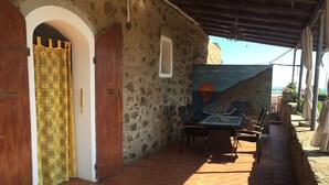 Un patio rústico al aire libre con un muro de piedra, una puerta de madera y una mesa con sillas.