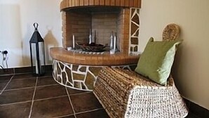 Ein gemütliches Zimmer mit Kamin aus Stein, einer gewobenen Bank und einer Laterne.