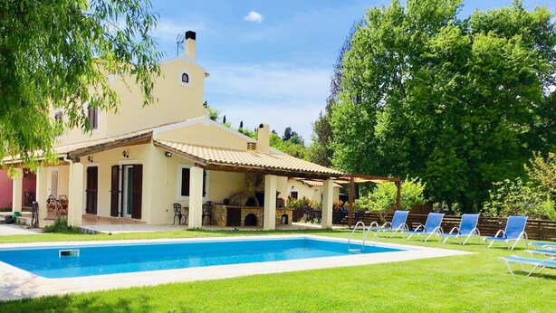 Ein Poolbereich mit Haus, Sitzgelegenheiten im Freien und einem Grill.