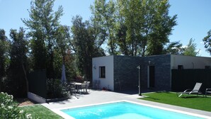 Ein Pool mit Liegestühlen, einer Grillgelegenheit und einer Steinmauer.