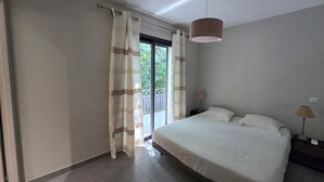 Ein Schlafzimmer mit Bett, Vorhängen, einem Nachttisch und einer Pendelleuchte.