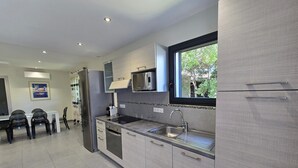 Eine moderne Küche mit Backofen, Spüle aus Edelstahl und einem Fenster mit Blick auf einen Garten.