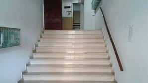 Una escalera con barandilla que conduce a un espacio interior con una puerta y un ventanal.
