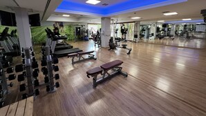 Un gimnasio con cintas de correr, máquinas de pesas y un muro de espejos.