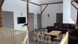 Un salón espacioso con un sofá de cuero marrón, una mesa de centro de madera y varios taburetes rústicos.