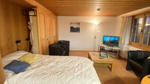 A cozy room with a bed, a desk, a chair, and a TV. - Quiet, centrally located apartment with unobstructed views of the mountains + north face of the Eiger! (Grindelwald)
