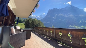 A terrace with wicker furniture and a view of mountains. - Quiet, centrally located apartment with unobstructed views of the mountains + north face of the Eiger! (Grindelwald)