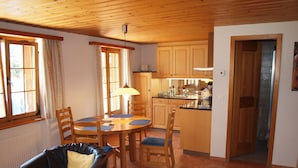 A cozy living room with a fireplace, a dining area with wooden furniture, and a kitchen with wooden cabinets and a sink. - Quiet, centrally located apartment with unobstructed views of the mountains + north face of the Eiger! (Grindelwald)
