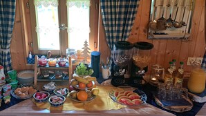 A breakfast buffet with various food items and beverages, a toaster, and kitchen utensils on a wooden table.