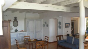 Un coin repas avec une table et des chaises en bois, un canapé bleu et une porte blanche avec un meuble placé à gauche.